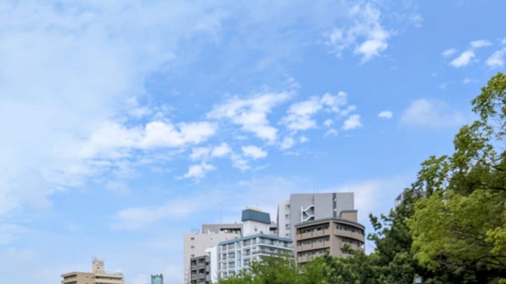 写真 青い空と雲と建物と木々の緑